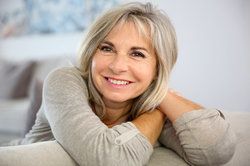 Silver-haired woman smiling after facial plastic surgery, her face looking youthful and free from wrinkles