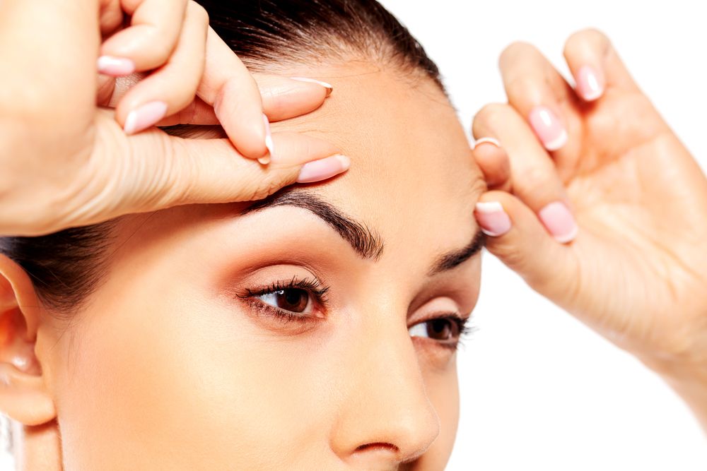 Woman lifting eyebrows with finger tips